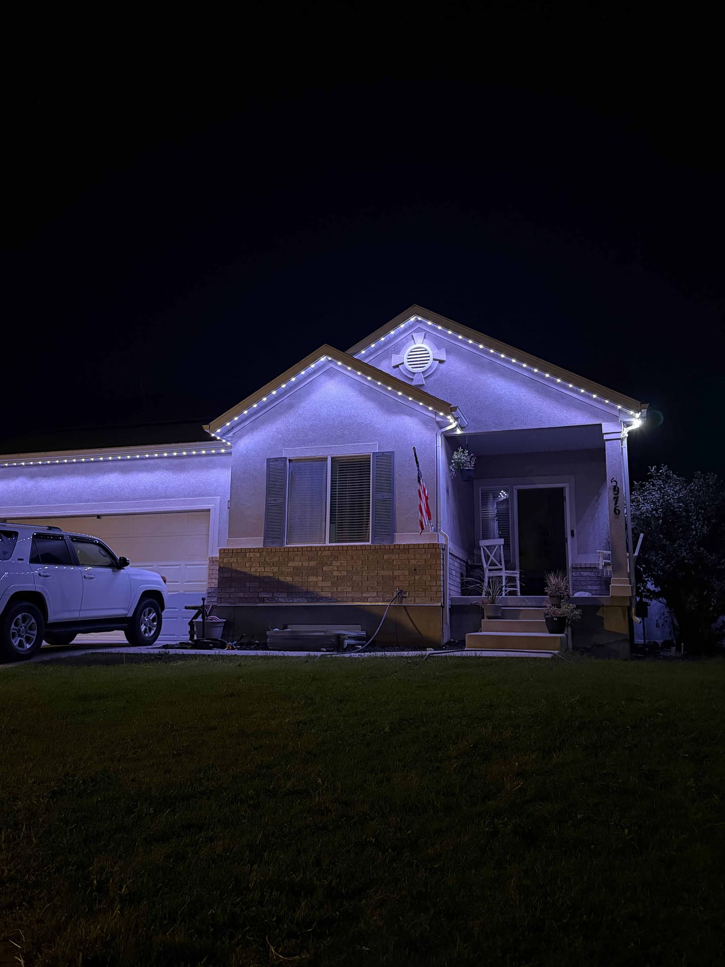 Stucco home lit cool white and purple with an American flag