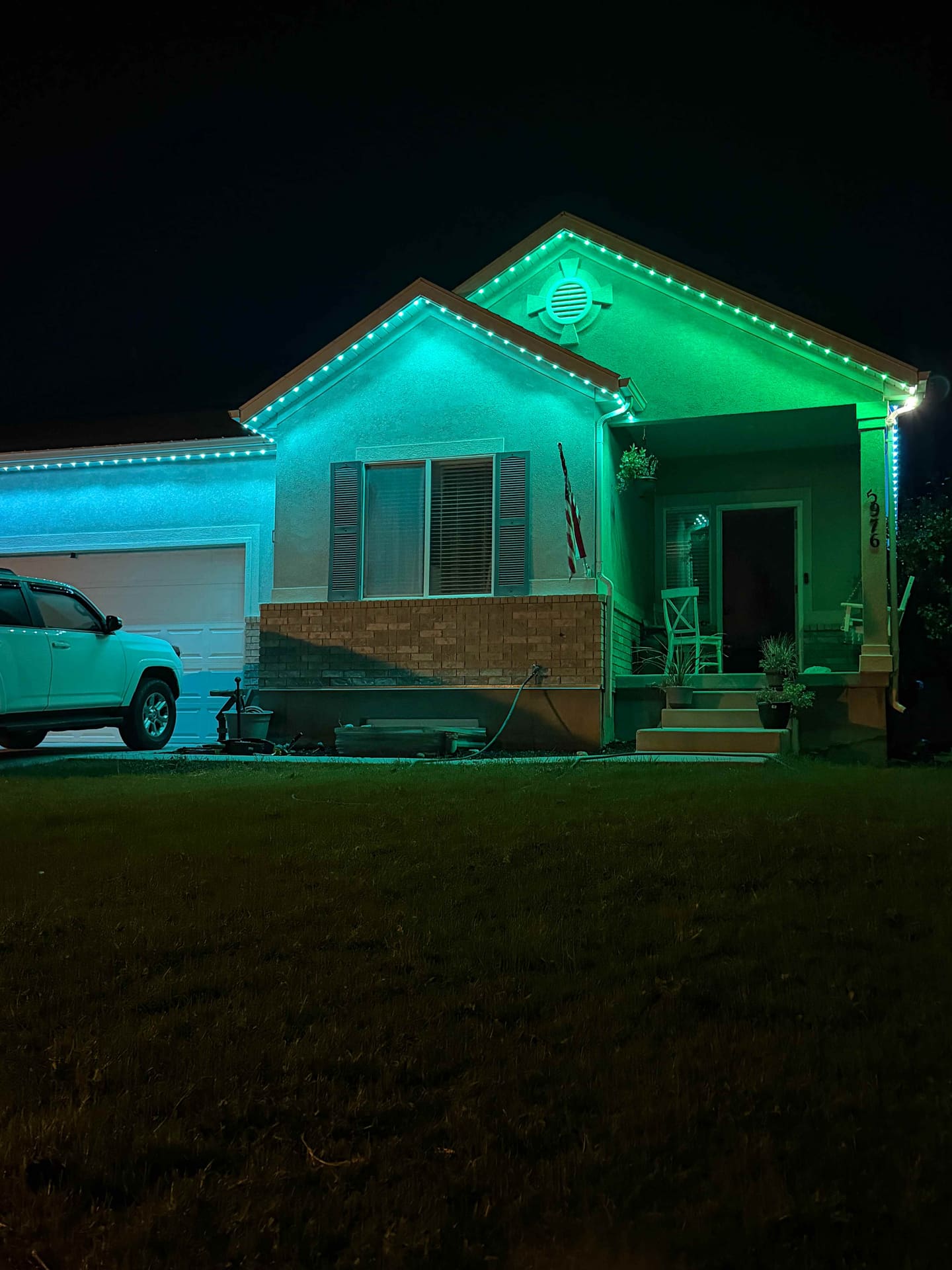 Stucco rambler lit green and teal at night