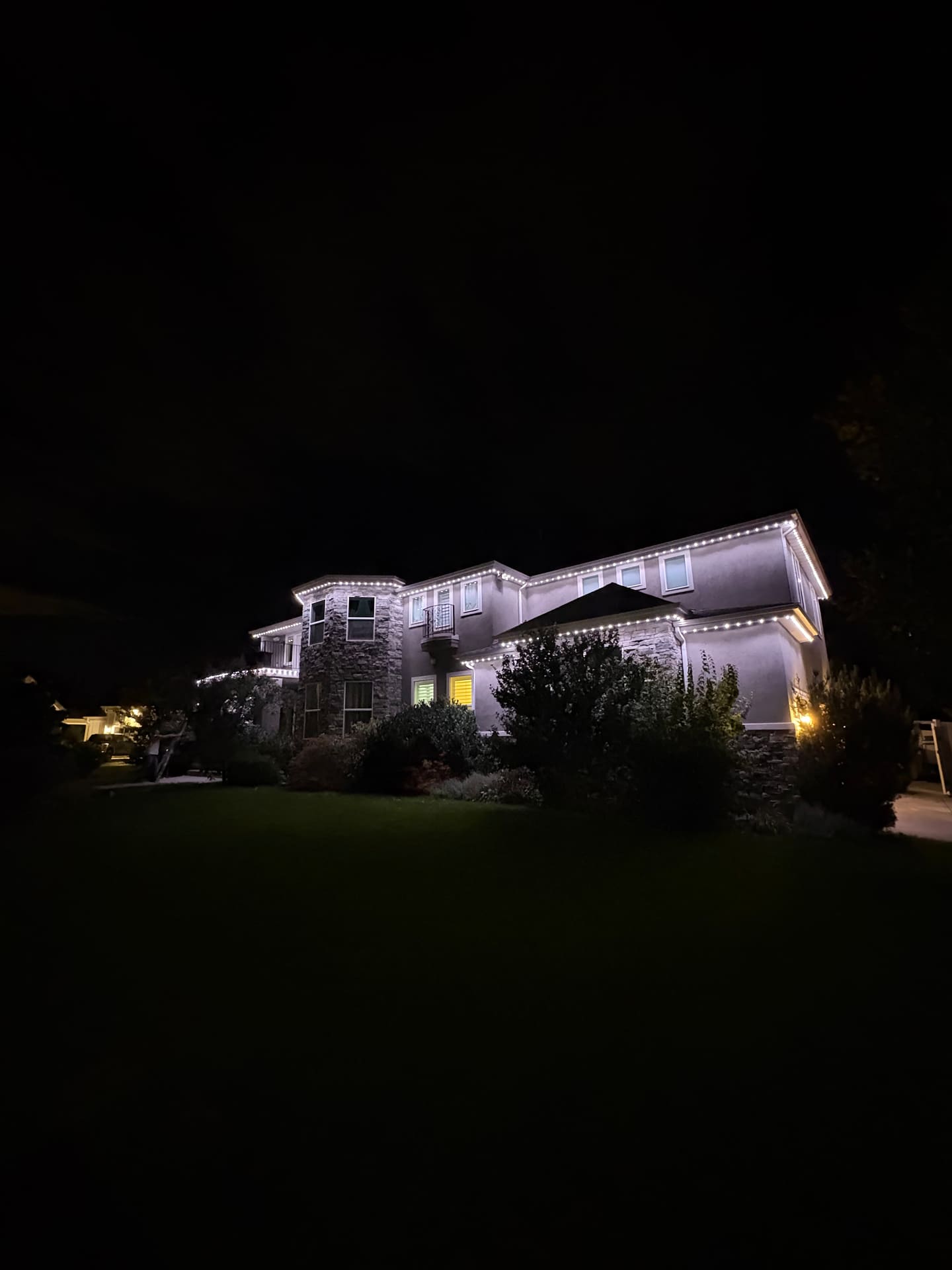 Large stucco and stone two-story home with crisp warm white roofline lighting at night