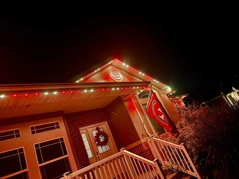 Home with red-and-white roofline lighting and a team flag