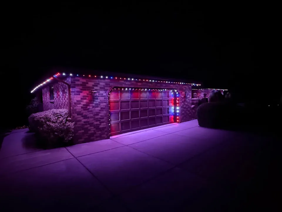 Brick home and garage with multicolor holiday roofline lighting