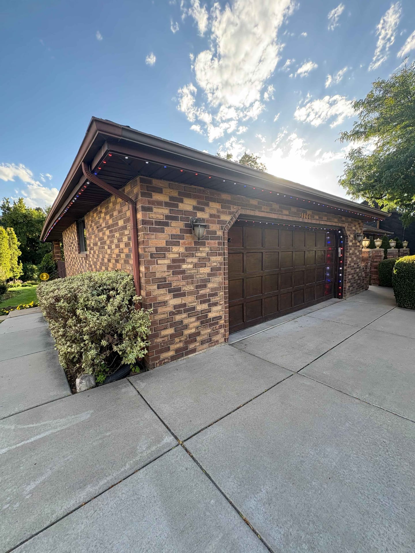 Wide view of the brown brick home with the color-matched track blending into the fascia