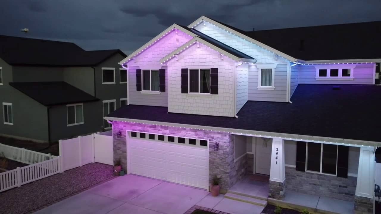 A home at dusk with purple and cool-white permanent roofline lighting